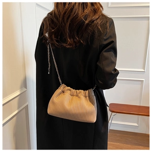 Detailed view of the pleated bucket bag showing the metal chain strap on a model shoulder