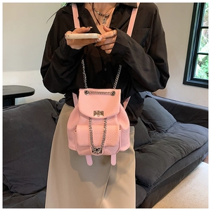 Detailed view of pink mini faux leather backpack with metallic chain straps on a model