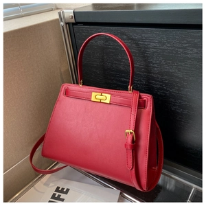 Close-up of red leather Kelly bag with gold twist lock and adjustable shoulder strap