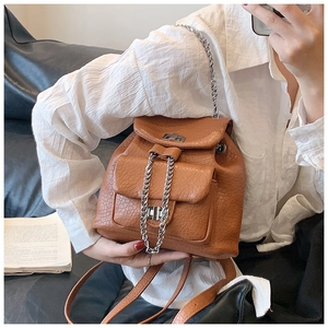 Close-up of brown crocodile texture backpack with silver twist locks and chain handle