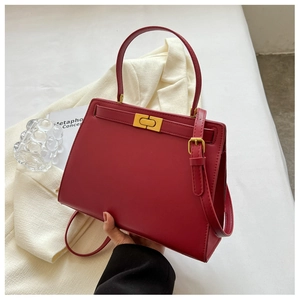 Detail of red leather crossbody bag featuring gold twist-lock and top handle