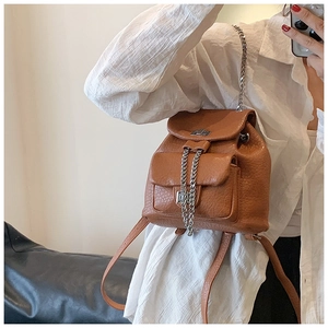 Close-up of brown pebbled leather mini backpack with silver chain and metal lock