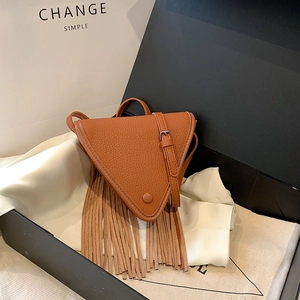 Sac triangle marron motif litchi avec de longues franges et une fine bandoulière sur coffret