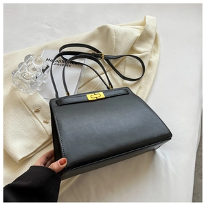 Detail of black leather Kelly bag with gold lock and adjustable shoulder strap