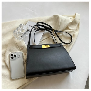 Detail of black leather bag with gold twist lock and slim strap in lifestyle setting