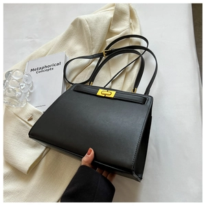 Detail of elegant black leather handbag with gold buckle on white fabric backdrop