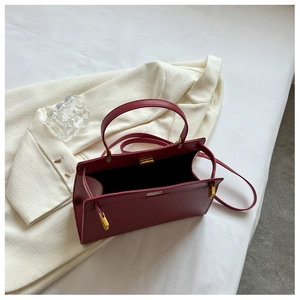 Detailed top view of a dark red faux leather Kelly bag with premium gold metal hardware
