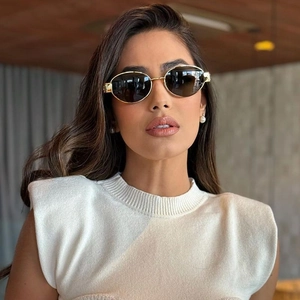 Detail of golden oval frame sunglasses featuring luxury metallic G logo on the temple