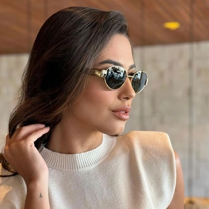 Detail view of oval women's sunglasses with golden frames and textured wide temples