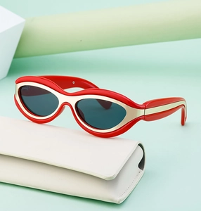 Dettaglio occhiali da sole cat-eye rossi con bordo in metallo oro e custodia bianca