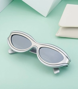 Dettaglio degli occhiali da sole cat-eye argento futuristici con lenti scure su sfondo menta