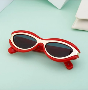 Dettaglio occhiali da sole Y2K cat-eye con montatura rossa e bordi in metallo dorato