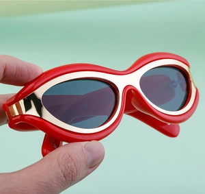 Dettaglio di occhiali da sole rossi cat-eye con accenti dorati e lenti grigio scuro