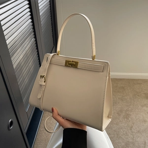 Elegant cream white leather Kelly bag with golden hardware and adjustable strap