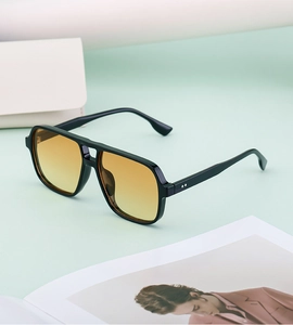 Detail of pilot sunglasses with black frame, yellow gradient lenses and metal studs