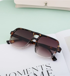 Detail of tortoise shell double-bridge pilot sunglasses on a green and white background