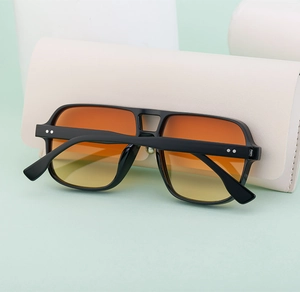 Close-up of retro double-bridge sunglasses with orange gradient lenses and metal rivet detail