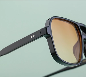 Close-up of double bridge sunglasses with metal hinge details and amber gradient lenses