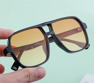 Detail of retro double-bridge sunglasses with bold black frame and yellow gradient lenses