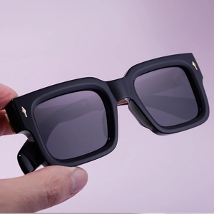 Nahaufnahme einer schwarzen eckigen Sonnenbrille mit goldfarbenen Pfeilakzenten