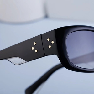 Close-up of black sports sunglasses featuring six golden star rivets on the temples