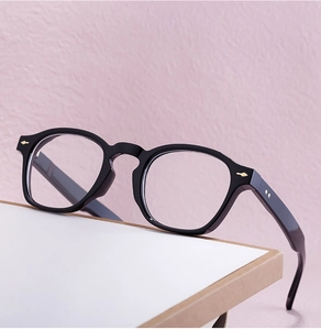 Close-up of black retro round eyeglass frames with gold rivets on textured background