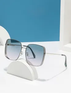 Close-up of square metal sunglasses featuring blue gradient lenses and rhinestone trim