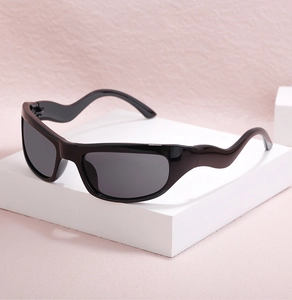 Close-up of black sports sunglasses with unique wavy temples on a white geometric stand