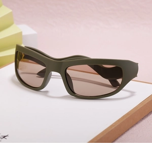 Close-up of olive green Y2K sports sunglasses with brown lenses on a modern prop