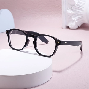 Classic black round frame glasses with golden diamond rivets on a white pedestal