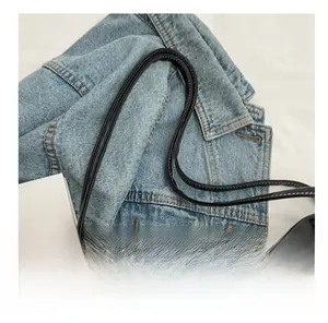 Detail view of smooth black leather bag handle decorated with a printed silk scarf