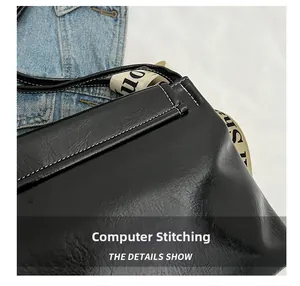 Close-up of black leather bag featuring white contrast stitching and letter printed strap