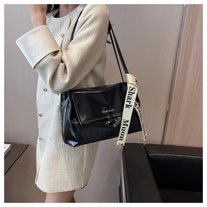 Detail of black leather crossbody bag with elegant printed scarf on the handle