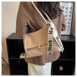 Detail view of beige glossy leather shoulder bag with embossed logo and decorative strap