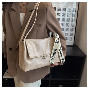 Detail of beige shoulder bag with metal buckle and Muon shark lettered strap decoration