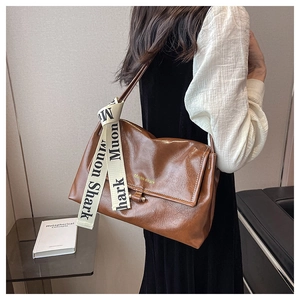 Brown crossbody bag with cream lettered ribbon and metallic buckle in a casual style