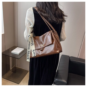 Detail of a dark brown vintage shoulder bag with a logo strap and metallic clasp closure