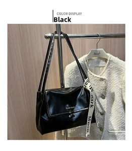 Detail of black glossy wrinkled PU bag with contrast white stitching and silk scarf