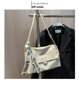Detail of off-white glossy shoulder bag with decorative logo silk scarf and metal clasp