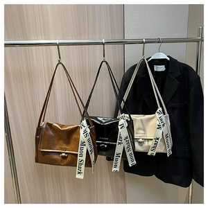 Detailed view of three minimalist shoulder bags in brown black and beige with logo straps