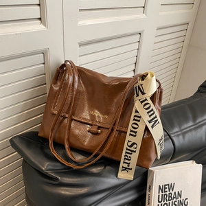 Minimalist brown oil wax leather shoulder bag with Muon Shark strap on a sofa