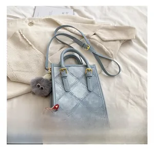 Detail of light blue quilted denim bag with gold hardware and plush monster charm