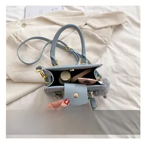 Internal capacity of light blue crossbody bag showing cosmetics and golden hardware