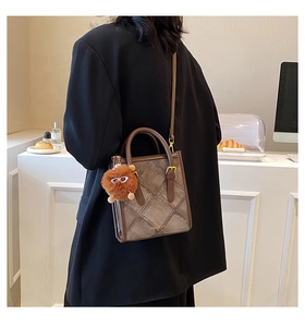 Brown leather crossbody bag featuring denim patchwork and a cute fur ball doll charm
