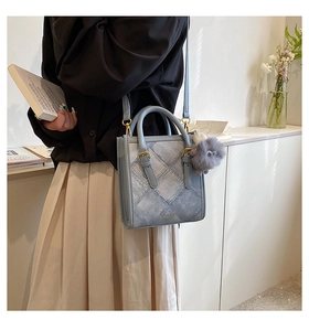 Detail of light blue denim texture tote bag with quilted stitching and gold hardware buckle