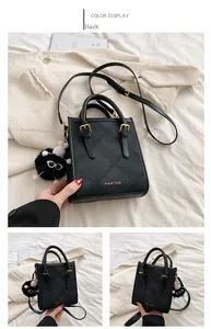Detail of black quilted tote bag with golden logo and decorative bicolor plush charm