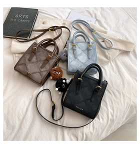 Three minimalist crossbody bags with quilted pattern and plush charms on a neutral bed