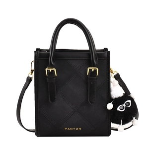 Classic black leather crossbody tote bag with twill embossing and plush monster charm