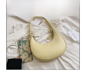 Top view of smooth yellow crescent shoulder bag with zipper detail on white fabric
