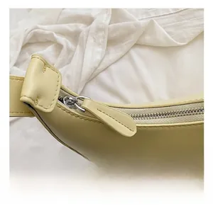 Detail view of smooth matte beige leather texture and silver zipper on shoulder bag